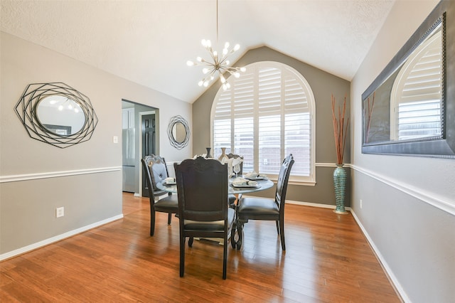 dining space featuring wood-type flooring, a textured ceiling, an inviting chandelier, and lofted ceiling