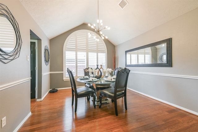 dining space with a chandelier, vaulted ceiling, and hardwood / wood-style flooring