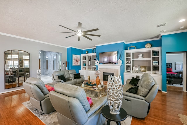 living room with ceiling fan, a fireplace, hardwood / wood-style floors, and a textured ceiling