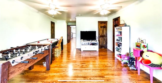 playroom with ceiling fan, ornamental molding, and hardwood / wood-style flooring