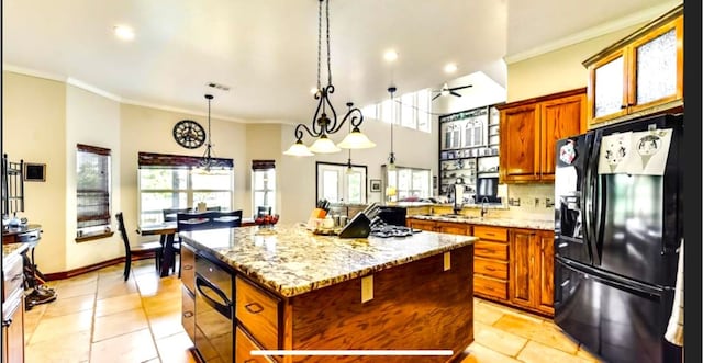 kitchen with decorative light fixtures, black appliances, light tile floors, and a kitchen island