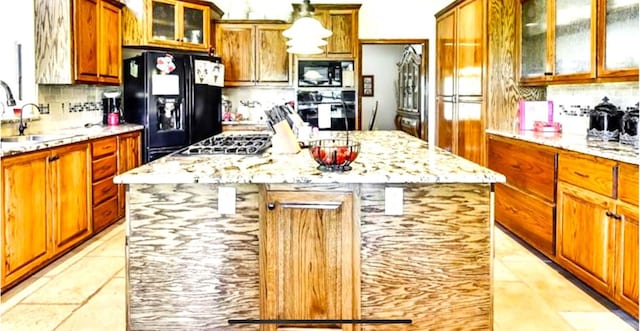 kitchen featuring sink, a kitchen island, black appliances, and backsplash