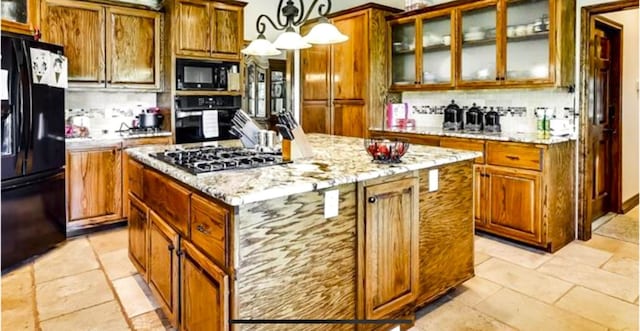 kitchen with tasteful backsplash, black appliances, a center island, light tile floors, and pendant lighting