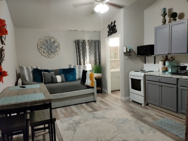 kitchen featuring vaulted ceiling, light hardwood / wood-style floors, white gas stove, gray cabinetry, and ceiling fan