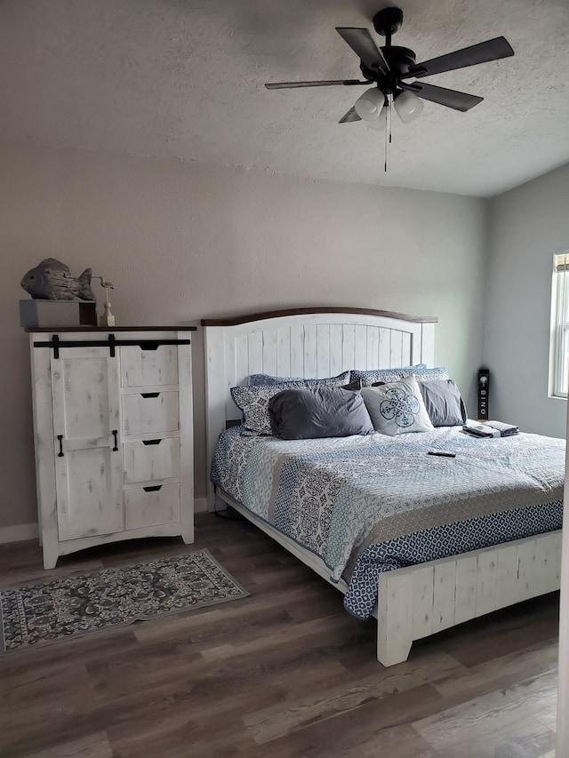 bedroom with ceiling fan, a textured ceiling, and dark wood-type flooring