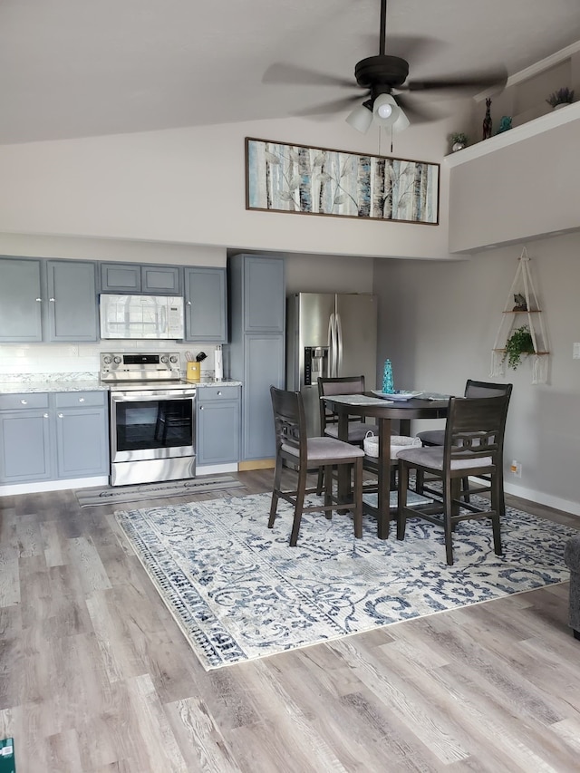 dining space with high vaulted ceiling, ceiling fan, and hardwood / wood-style flooring