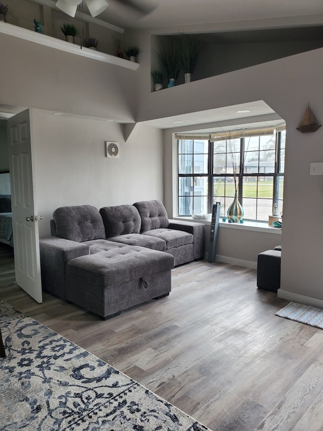 living room with a high ceiling, ceiling fan, and wood-type flooring