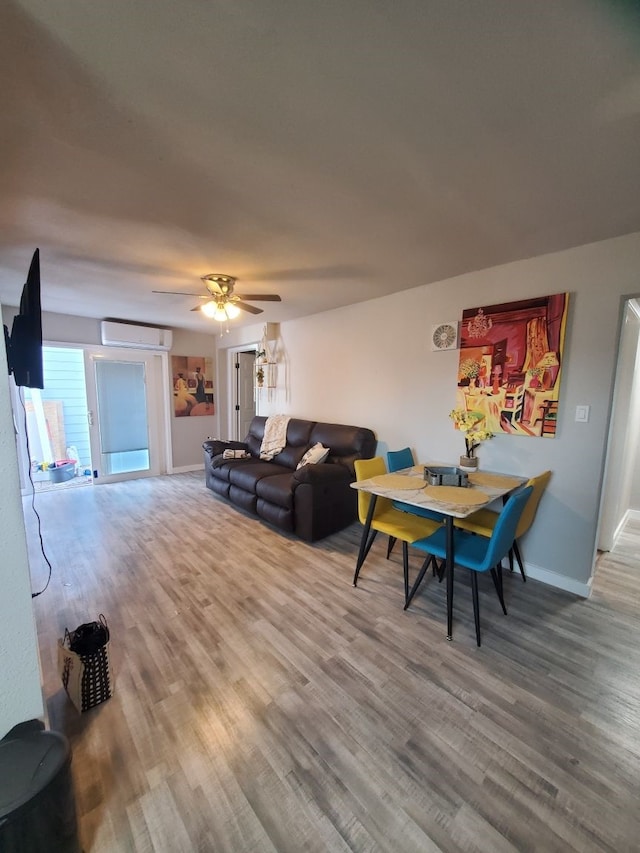 living room featuring a wall unit AC, ceiling fan, and wood-type flooring