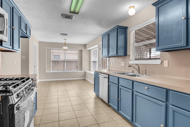 kitchen with blue cabinetry, light tile flooring, pendant lighting, sink, and appliances with stainless steel finishes