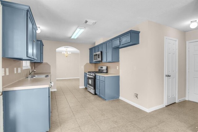 kitchen with stainless steel appliances, sink, blue cabinetry, and light tile floors