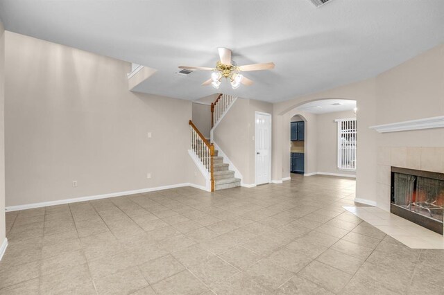 unfurnished living room with ceiling fan, a tile fireplace, and light tile floors