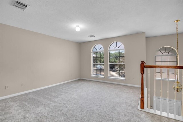 carpeted spare room featuring a textured ceiling