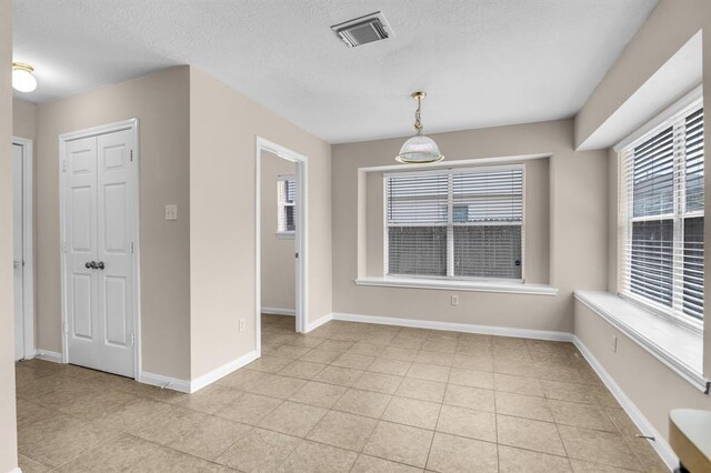 tiled empty room featuring a healthy amount of sunlight and a textured ceiling