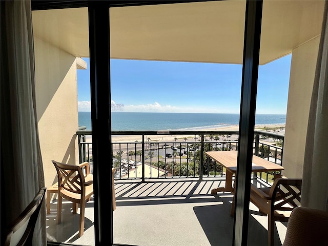 balcony with a water view and a view of the beach