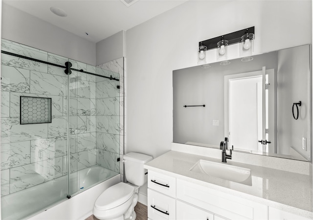 full bathroom featuring toilet, combined bath / shower with glass door, and vanity