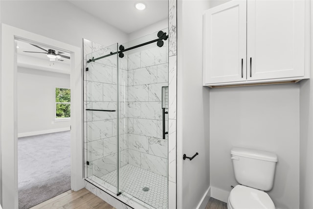 bathroom with hardwood / wood-style floors, toilet, an enclosed shower, and ceiling fan