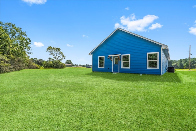 rear view of house featuring cooling unit and a lawn