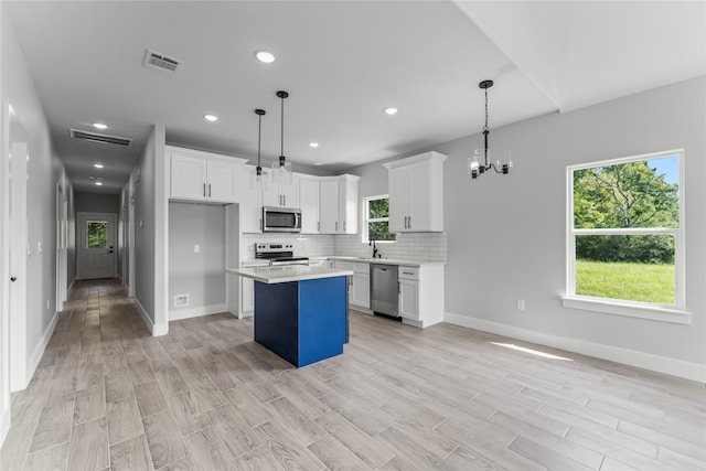 kitchen with a center island, a healthy amount of sunlight, stainless steel appliances, and hanging light fixtures