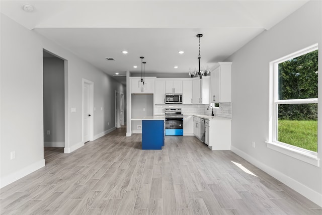 kitchen with stainless steel appliances, sink, pendant lighting, white cabinets, and a kitchen island