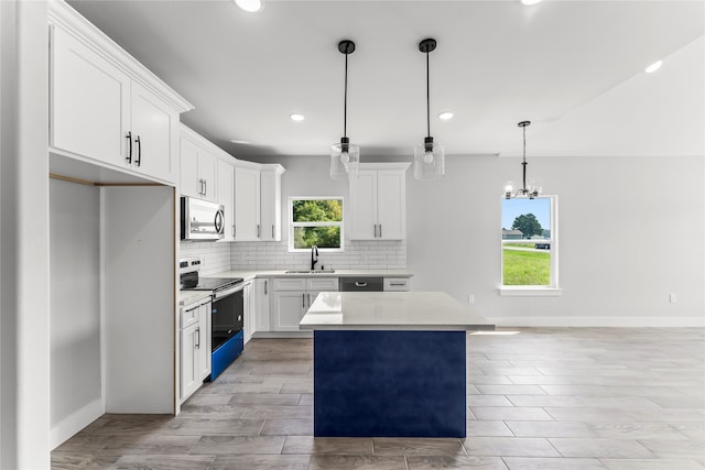 kitchen featuring range with electric stovetop, a kitchen island, a healthy amount of sunlight, and white cabinetry