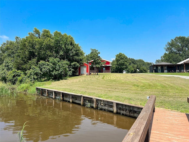 view of dock with a lawn and a water view