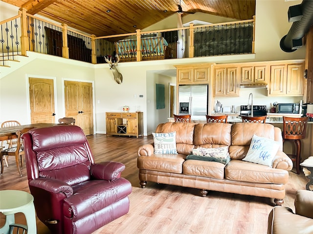 living room featuring a towering ceiling, light wood-type flooring, and wooden ceiling