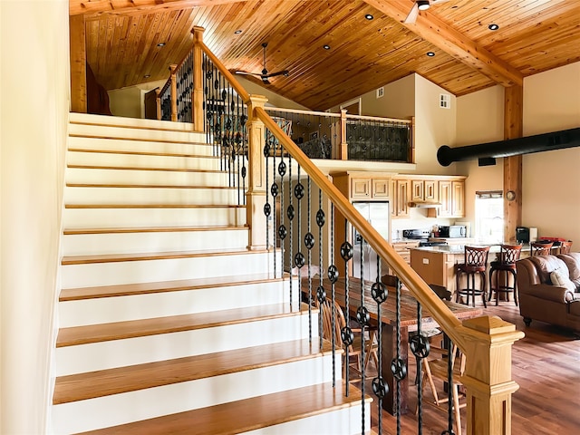 stairway with beamed ceiling, wooden ceiling, hardwood / wood-style flooring, high vaulted ceiling, and ceiling fan