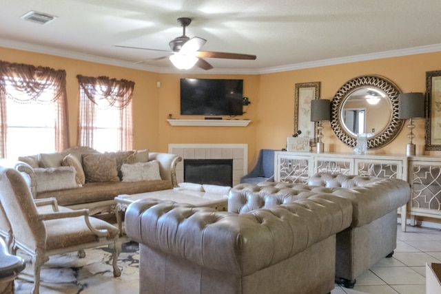 living room with a tiled fireplace, ceiling fan, ornamental molding, and light tile patterned flooring