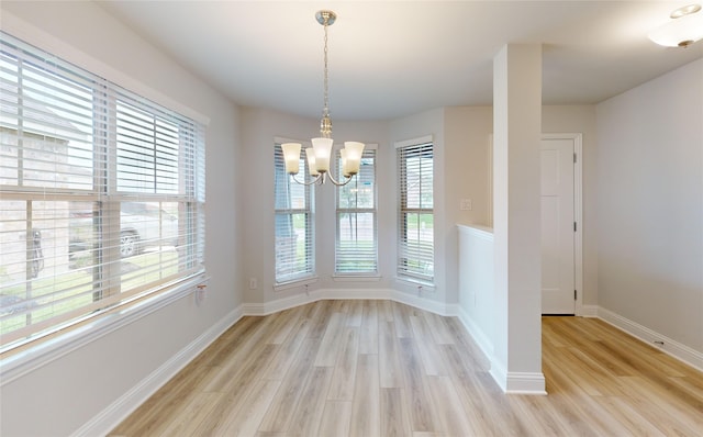 unfurnished dining area with a notable chandelier and light wood-type flooring