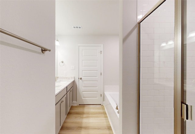 bathroom with vanity, hardwood / wood-style flooring, and plus walk in shower
