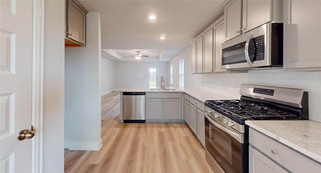 kitchen with light hardwood / wood-style flooring, stainless steel appliances, gray cabinetry, sink, and ceiling fan