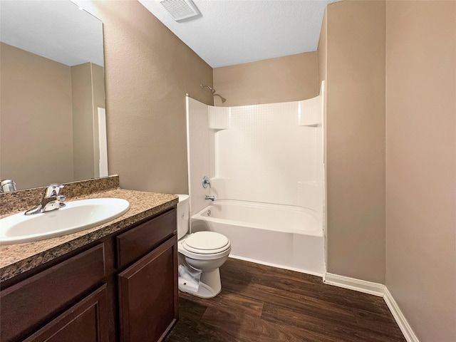 full bathroom featuring hardwood / wood-style flooring, tub / shower combination, vanity, a textured ceiling, and toilet