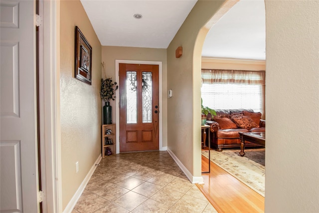 entrance foyer featuring crown molding and light tile floors