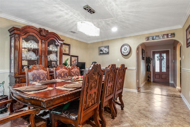 dining room with tile flooring, ornamental molding, and a chandelier