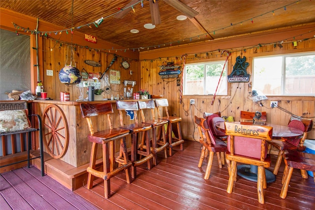 dining room with wood walls, hardwood / wood-style flooring, wood ceiling, and indoor bar