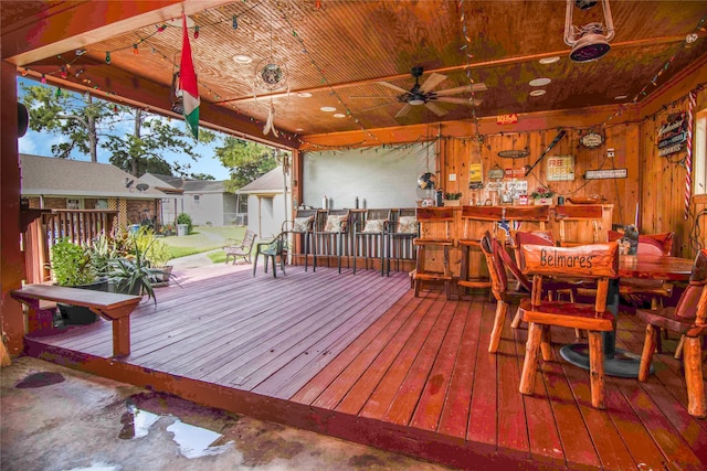 wooden terrace featuring ceiling fan and a bar