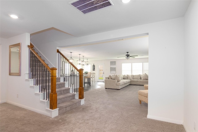 unfurnished living room featuring carpet flooring and ceiling fan with notable chandelier