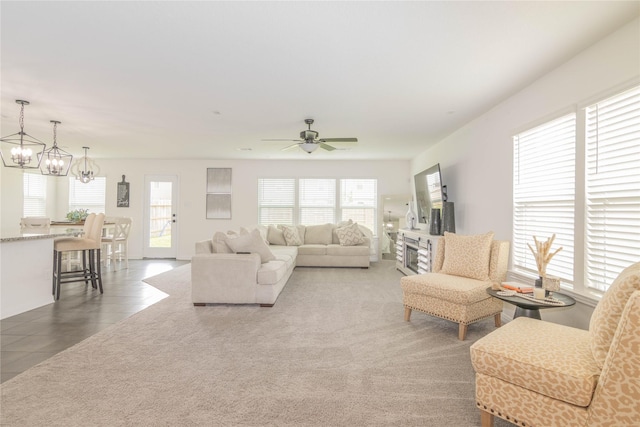 living room featuring dark colored carpet and ceiling fan with notable chandelier