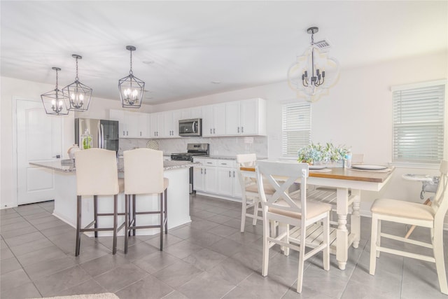 kitchen featuring white cabinets, a kitchen breakfast bar, hanging light fixtures, a center island, and stainless steel appliances