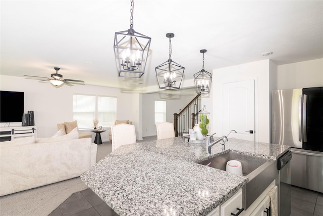 kitchen featuring white cabinets, hanging light fixtures, a kitchen island with sink, stainless steel appliances, and light stone countertops