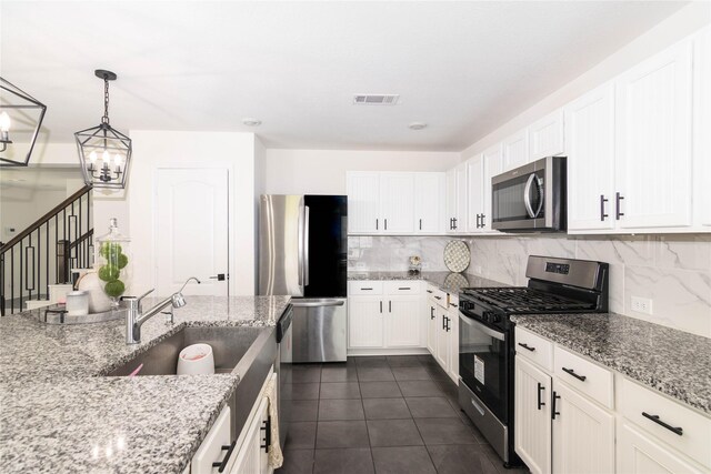 kitchen featuring stainless steel appliances, white cabinetry, hanging light fixtures, and light stone counters