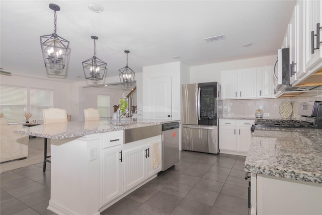 kitchen featuring stainless steel appliances, an island with sink, and white cabinets