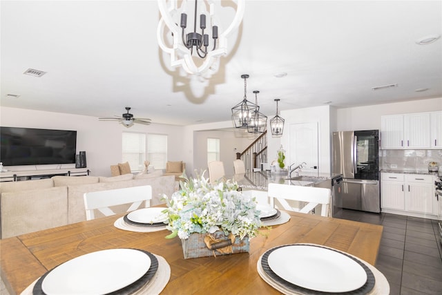 tiled dining space with sink and ceiling fan with notable chandelier