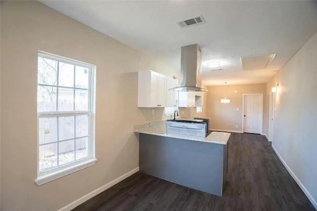 kitchen with light stone counters, wall chimney range hood, dark hardwood / wood-style flooring, and kitchen peninsula