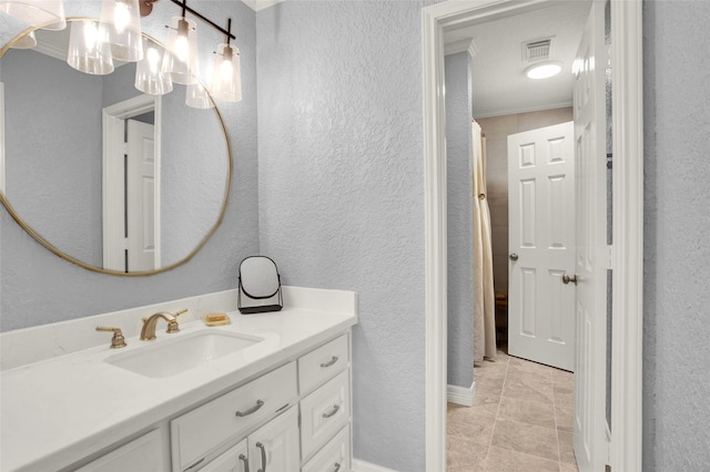 bathroom featuring tile patterned flooring, vanity, and crown molding