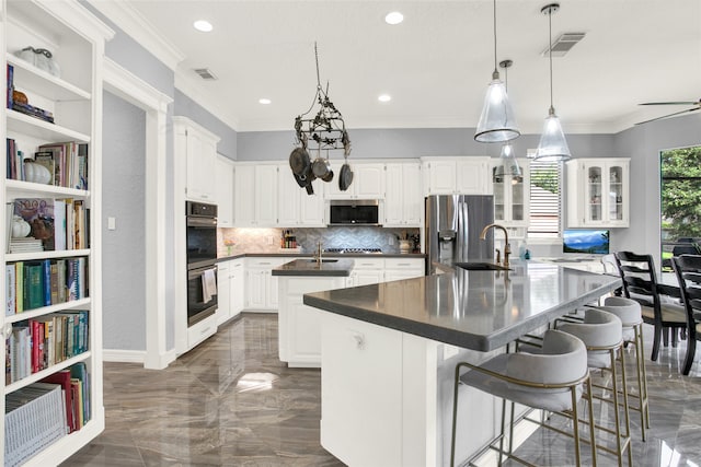 kitchen with white cabinetry, a kitchen island with sink, a kitchen breakfast bar, and appliances with stainless steel finishes