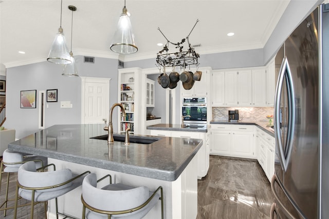 kitchen featuring white cabinets, sink, stainless steel appliances, and an island with sink