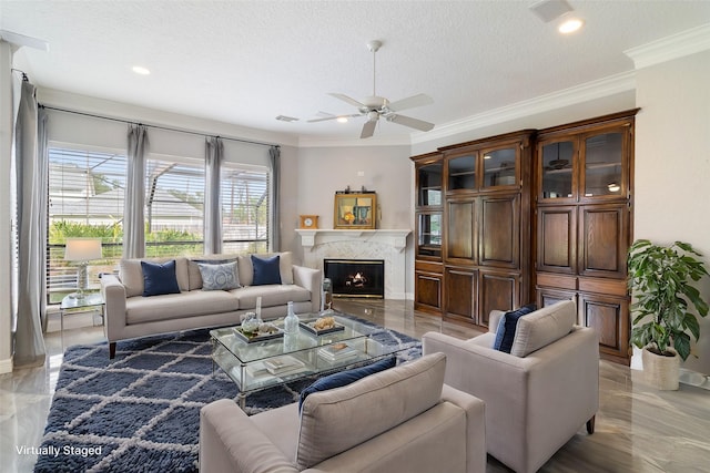 living room featuring ceiling fan, crown molding, a premium fireplace, and a textured ceiling