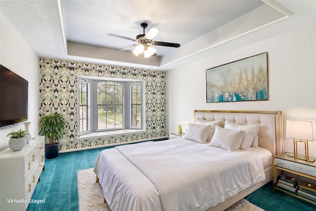 bedroom featuring carpet, a raised ceiling, and ceiling fan