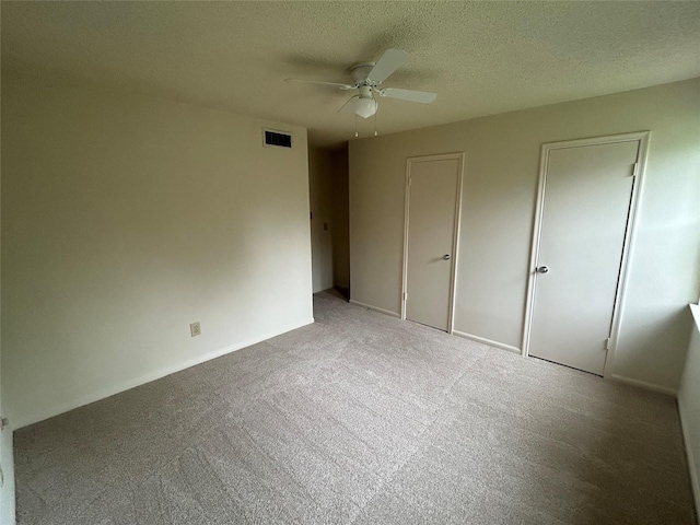 unfurnished bedroom with ceiling fan, light colored carpet, and a textured ceiling